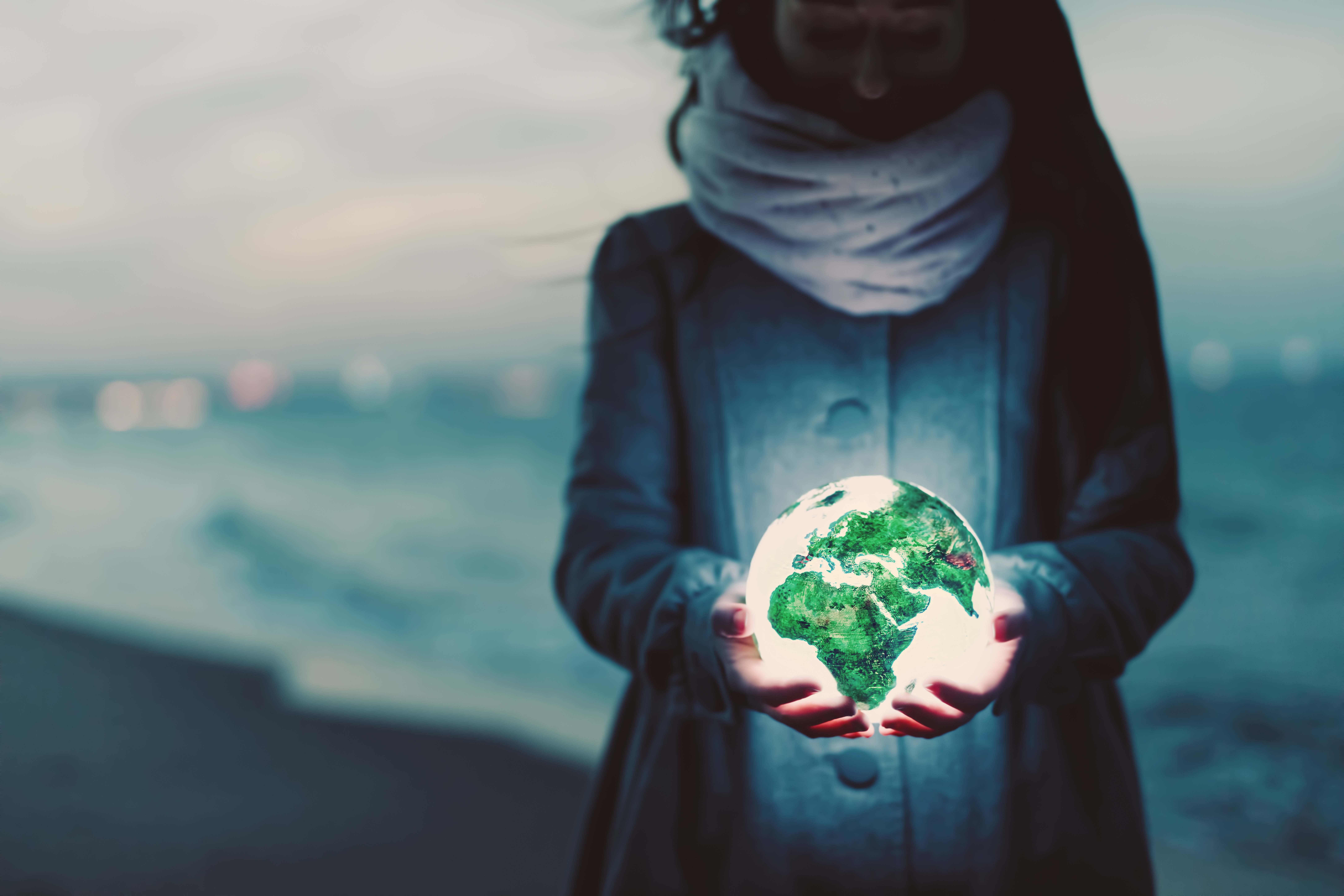 earth-globe-glowing-in-womans-hands-on-the-beach-a-TJ2ABV3_envato_low res